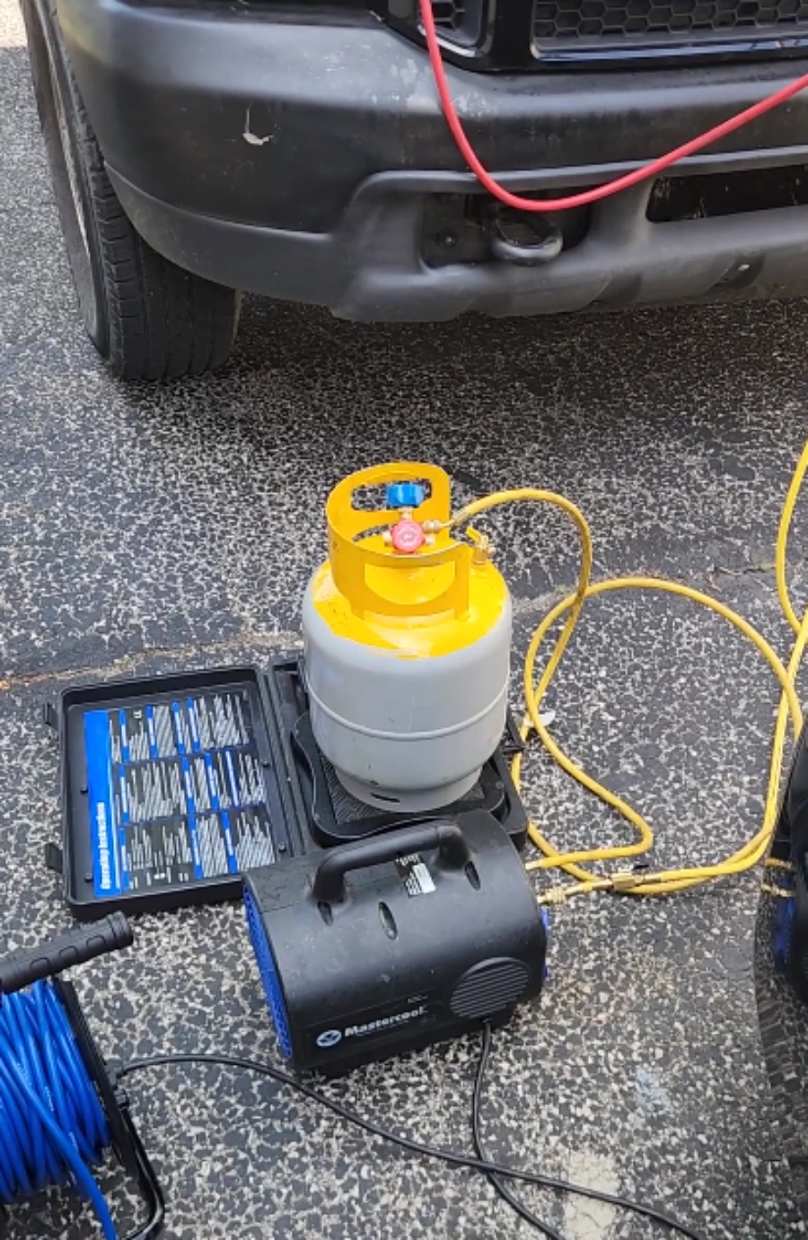 Refrigerant recovery and recharge equipment set up beside a car