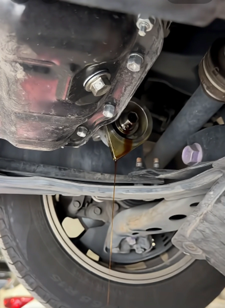 Oil pan and drain plug underneath a car before an oil change