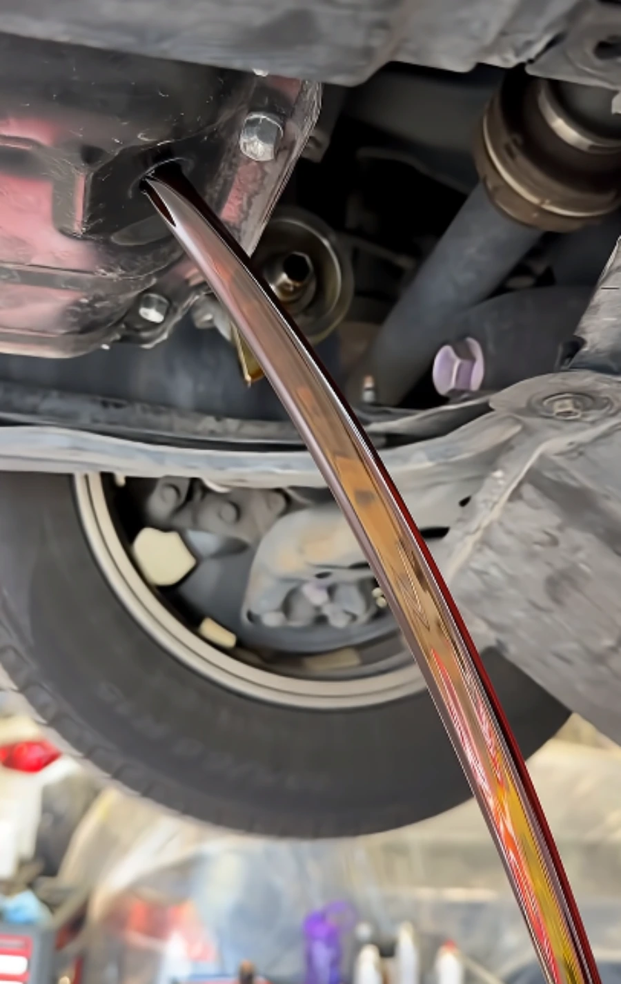 Old engine oil draining from the oil pan during an oil change